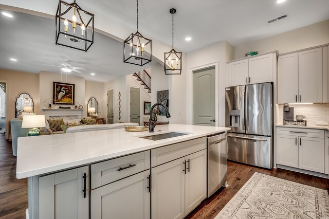 kitchen with tasteful backsplash, appliances with stainless steel finishes, light countertops, and a sink