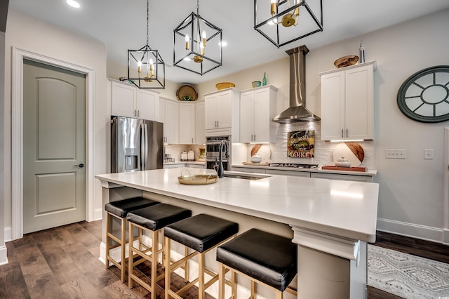 kitchen featuring stainless steel appliances, dark wood-type flooring, white cabinetry, wall chimney range hood, and tasteful backsplash