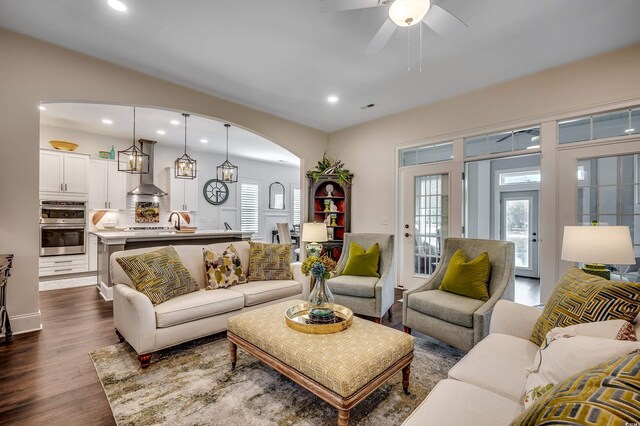 living room with dark wood finished floors, recessed lighting, arched walkways, and ceiling fan