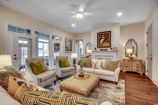 living room with a ceiling fan, wood finished floors, recessed lighting, french doors, and a stone fireplace