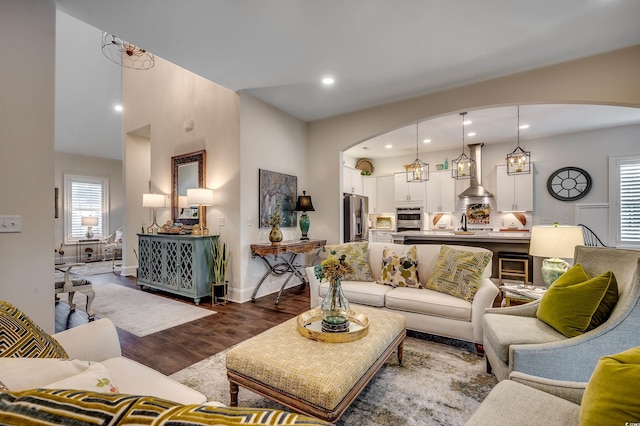 living room featuring recessed lighting, baseboards, arched walkways, and wood finished floors