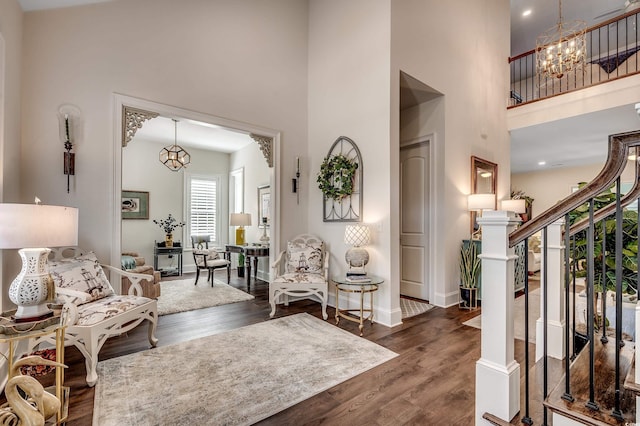 living room featuring stairs, a high ceiling, dark wood-style flooring, and a chandelier