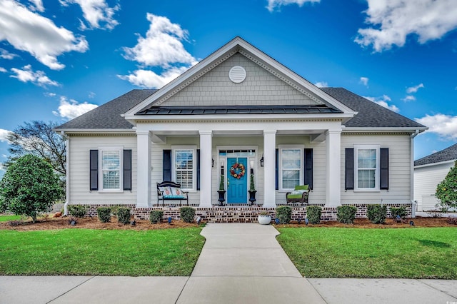 neoclassical / greek revival house with a standing seam roof, a front lawn, covered porch, and roof with shingles