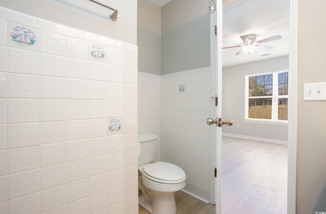 bathroom with ceiling fan, toilet, wood finished floors, and a textured ceiling