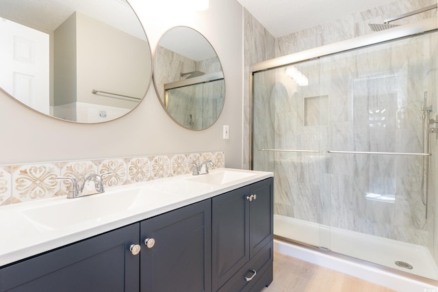 full bath featuring a sink, double vanity, and a shower stall