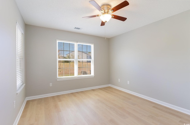 spare room with baseboards, visible vents, light wood finished floors, and ceiling fan