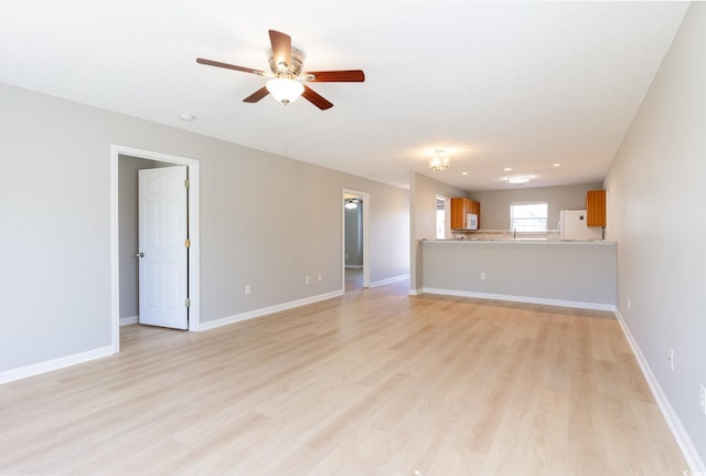 unfurnished living room with a ceiling fan, baseboards, and light wood finished floors