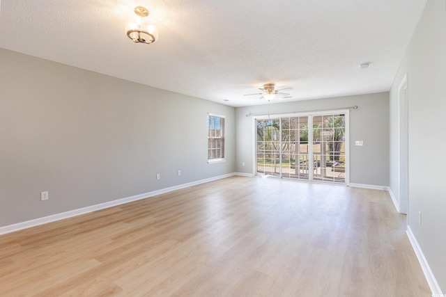 empty room featuring ceiling fan, baseboards, a textured ceiling, and light wood-style flooring