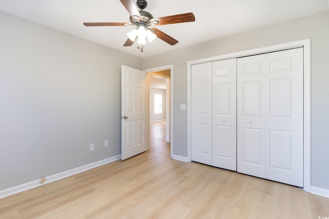 unfurnished bedroom with a closet, ceiling fan, light wood-type flooring, and baseboards