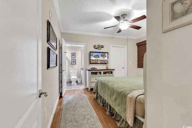 bedroom featuring ensuite bathroom, wood finished floors, crown molding, baseboards, and ceiling fan