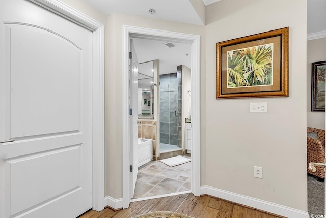 hall featuring light wood-style flooring and baseboards