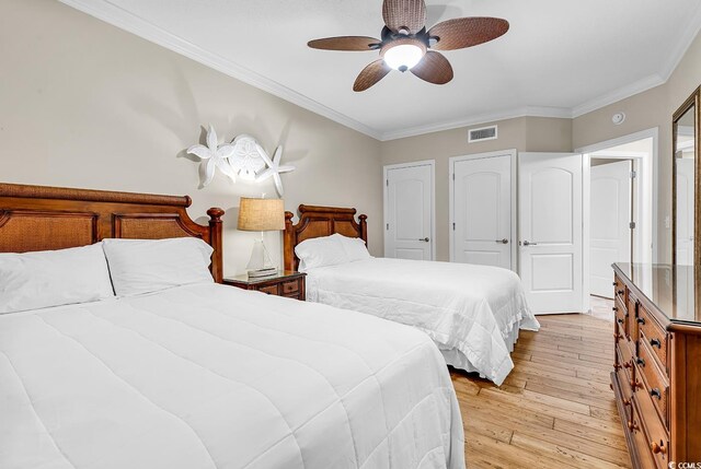 bedroom featuring visible vents, a ceiling fan, light wood-style floors, and ornamental molding