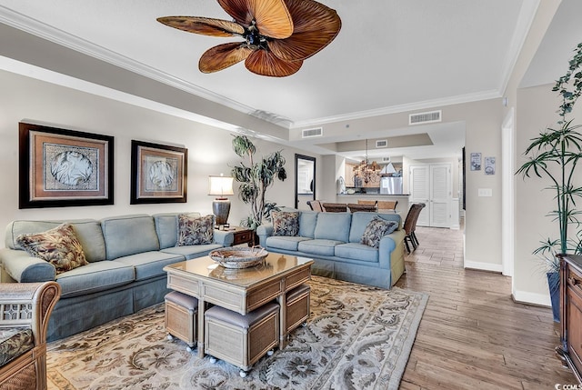 living room featuring light wood-type flooring, visible vents, baseboards, and crown molding