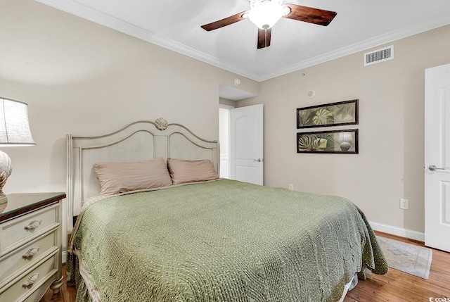 bedroom featuring wood finished floors, baseboards, visible vents, ceiling fan, and ornamental molding
