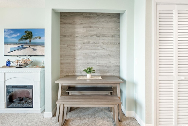 dining room with a glass covered fireplace, baseboards, and carpet floors