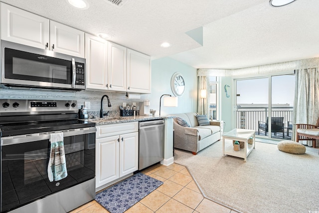 kitchen with light tile patterned floors, white cabinetry, stainless steel appliances, and a sink