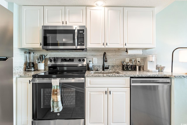 kitchen featuring backsplash, white cabinets, stainless steel appliances, and a sink