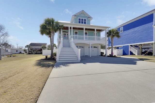 raised beach house with a porch, stairway, an attached garage, and driveway