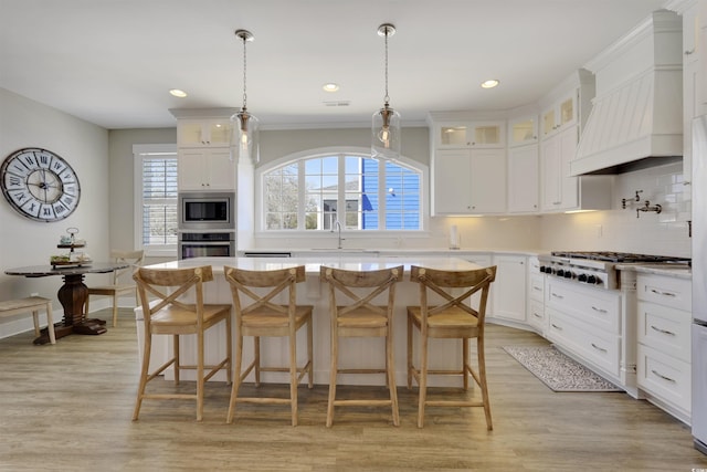 kitchen with a sink, backsplash, stainless steel appliances, light countertops, and custom exhaust hood