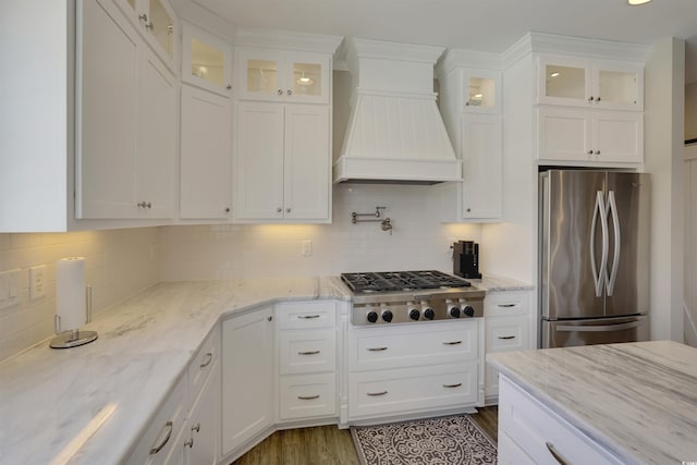 kitchen featuring backsplash, premium range hood, stainless steel appliances, white cabinetry, and dark wood-style flooring