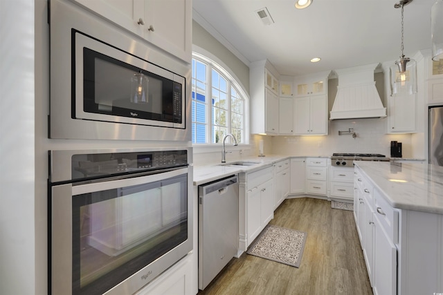 kitchen with visible vents, custom range hood, a sink, tasteful backsplash, and stainless steel appliances