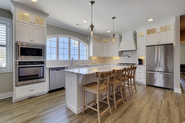 kitchen featuring visible vents, premium range hood, a kitchen island, appliances with stainless steel finishes, and tasteful backsplash