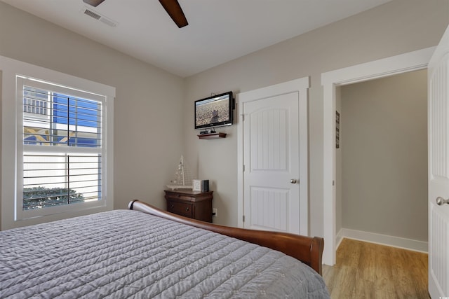 bedroom featuring a ceiling fan, wood finished floors, visible vents, and baseboards