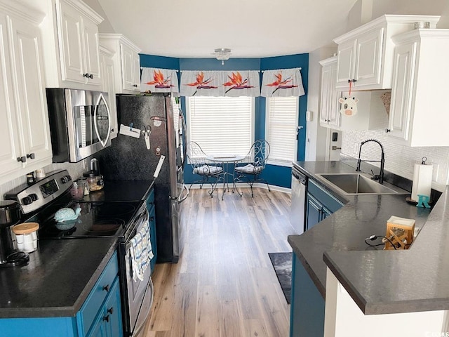 kitchen featuring a sink, dark countertops, blue cabinets, and stainless steel appliances