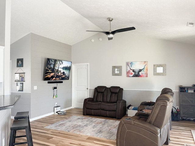 living room featuring visible vents, a textured ceiling, light wood finished floors, lofted ceiling, and ceiling fan