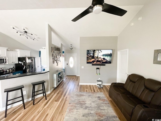 living area featuring light wood-type flooring, baseboards, a ceiling fan, and vaulted ceiling