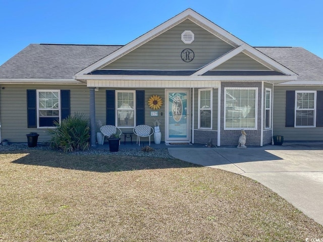 view of front of property with a front lawn, covered porch, and roof with shingles