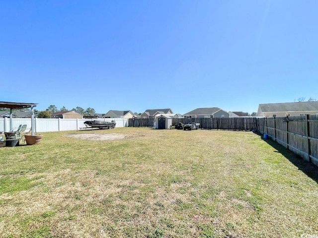 view of yard with an outbuilding, a fenced backyard, and a shed