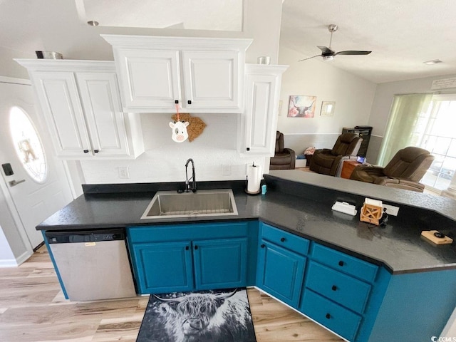 kitchen featuring dark countertops, stainless steel dishwasher, white cabinetry, blue cabinets, and a sink