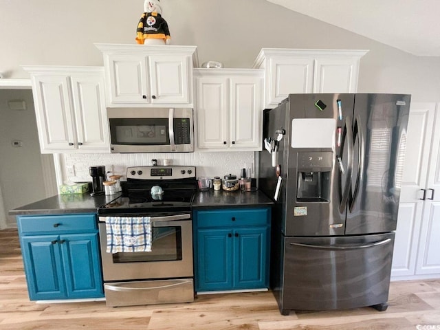 kitchen with blue cabinetry, stainless steel appliances, dark countertops, and white cabinetry