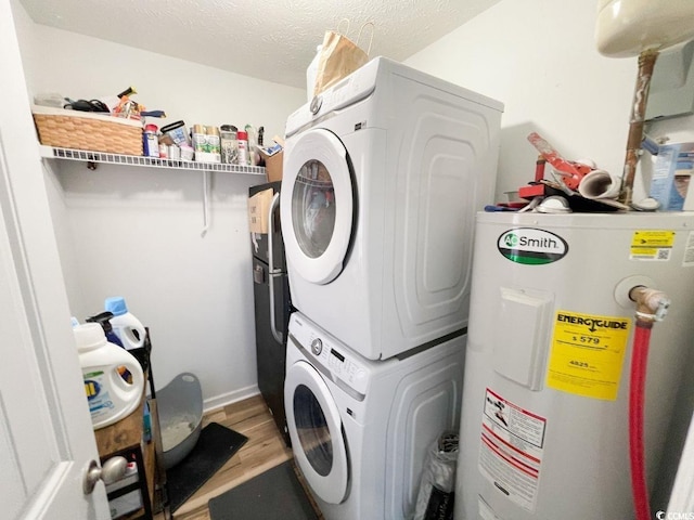 laundry room featuring laundry area, light wood-style flooring, water heater, stacked washer and clothes dryer, and a textured ceiling