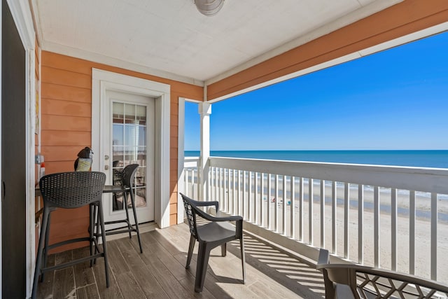 balcony featuring a view of the beach and a water view