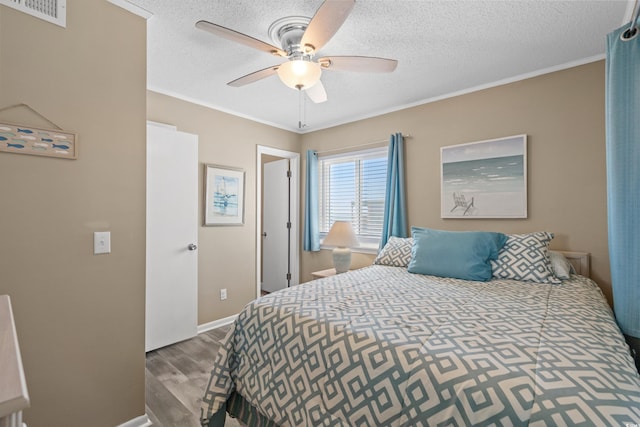 bedroom with crown molding, wood finished floors, visible vents, and a textured ceiling