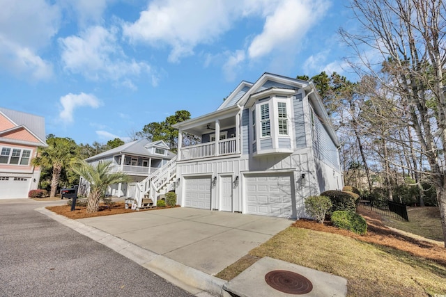 view of front of house featuring ceiling fan, stairs, concrete driveway, a garage, and board and batten siding