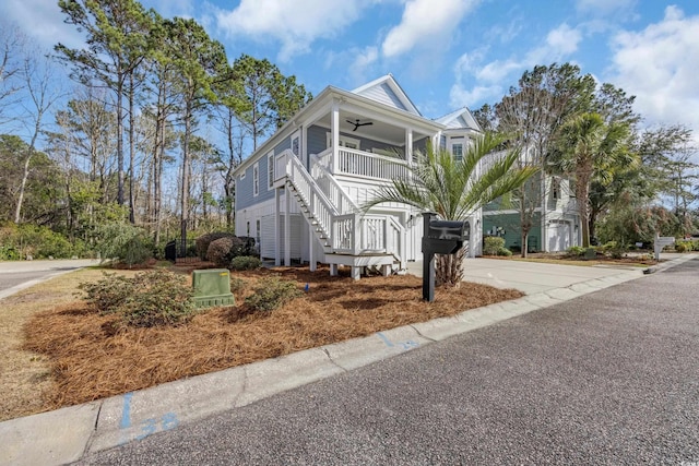 raised beach house featuring covered porch, ceiling fan, and stairs