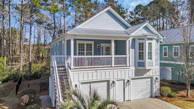 view of front of property featuring board and batten siding, a porch, concrete driveway, stairs, and a standing seam roof