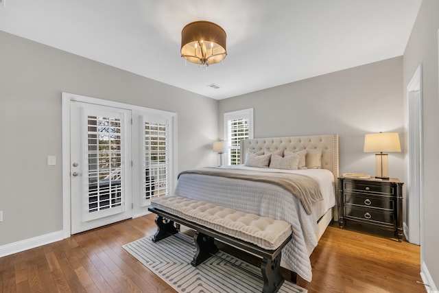 bedroom with hardwood / wood-style floors, visible vents, baseboards, and access to exterior