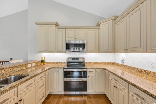 kitchen featuring cream cabinetry, appliances with stainless steel finishes, a sink, and vaulted ceiling