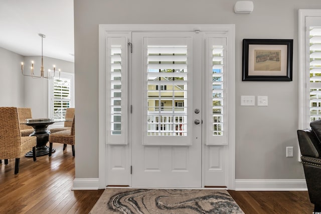 foyer with a notable chandelier, baseboards, and dark wood-type flooring