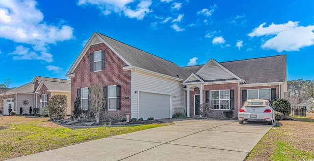 traditional-style home with a garage, brick siding, concrete driveway, and a front yard