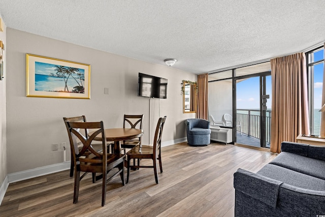 dining area with expansive windows, a healthy amount of sunlight, and wood finished floors