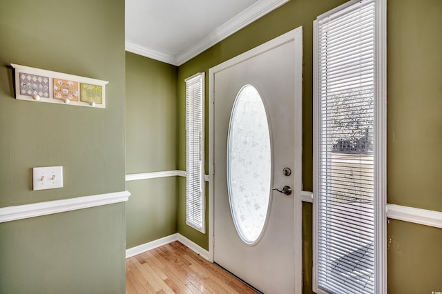 foyer entrance featuring a healthy amount of sunlight, crown molding, baseboards, and hardwood / wood-style flooring