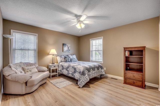 bedroom with baseboards, a textured ceiling, and wood finished floors