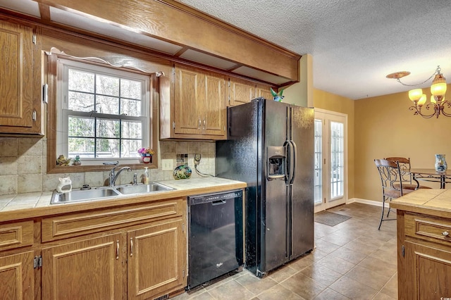 kitchen with a sink, black appliances, and tile countertops