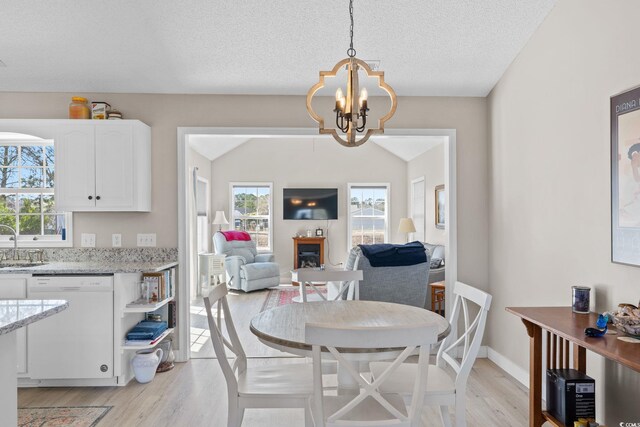 2029 Hawksmoor Dr, Conway, SC 29526 - dining area featuring light wood-style flooring, plenty of natural light, an inviting chandelier, and a glass covered fireplace
