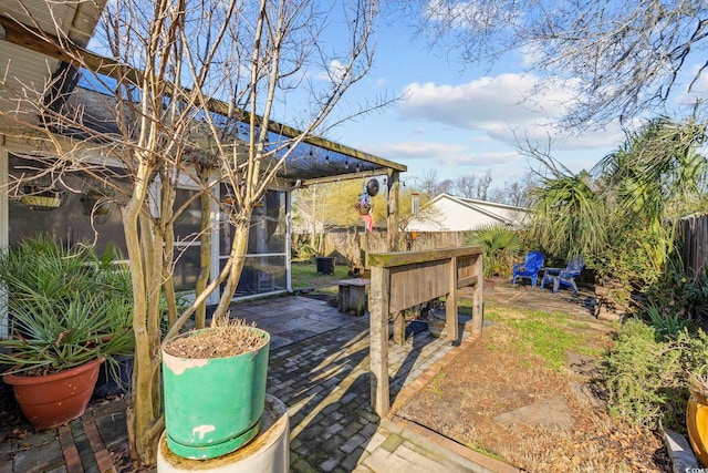 view of yard with a patio area, a fenced backyard, and a sunroom